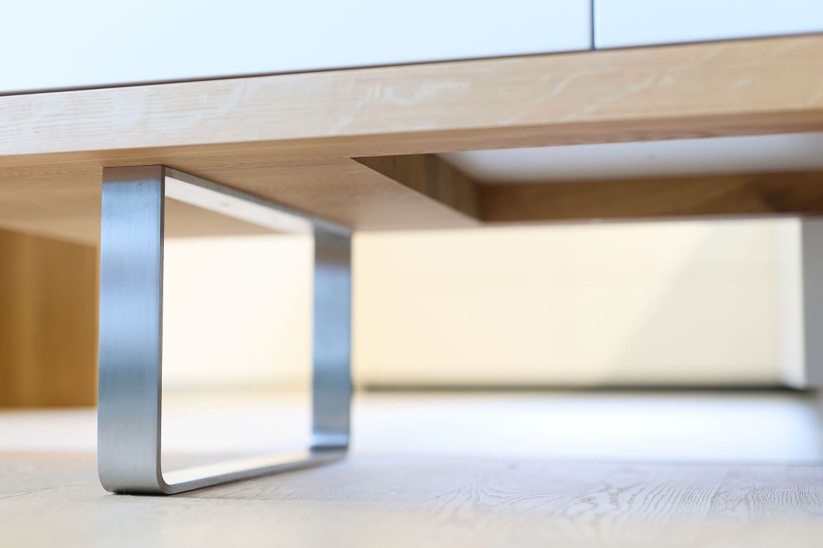 Detailaufnahme eines maßgefertigten Sideboards mit Eiche-Passepartout und modernem Edelstahlfuß