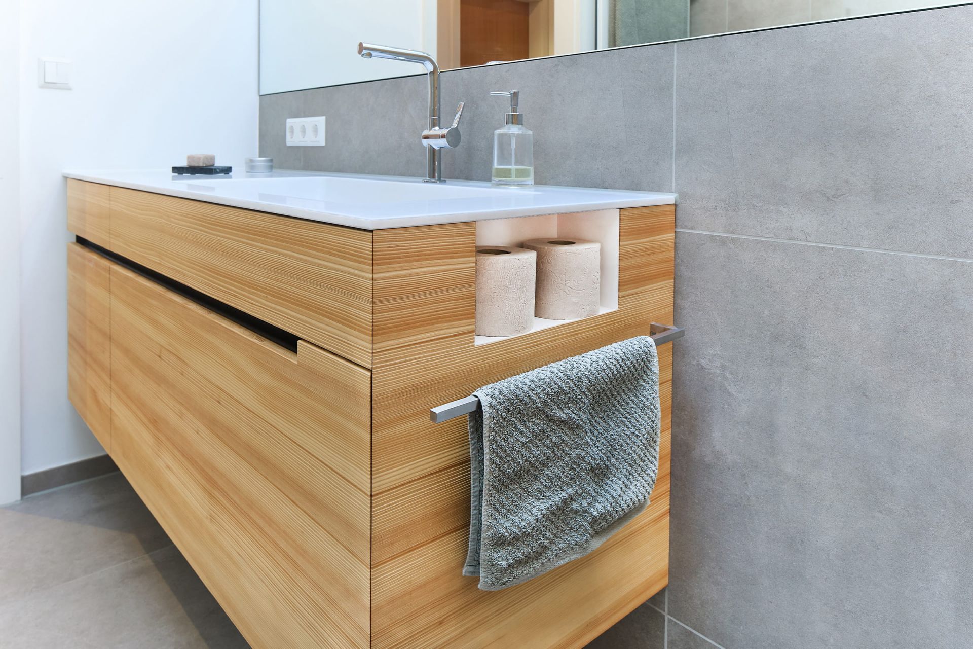 Moderner Holzwaschtisch mit integrierten Ablagefächern, Handtuchhalter und klarer Linienführung in einem stilvollen Bad.