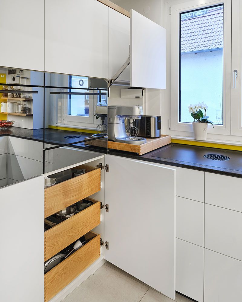 Maßgefertigte Schreinerküche mit Innenauszügen aus Holz und Oberschrank mit Klappenlift für komfortable Bedienung