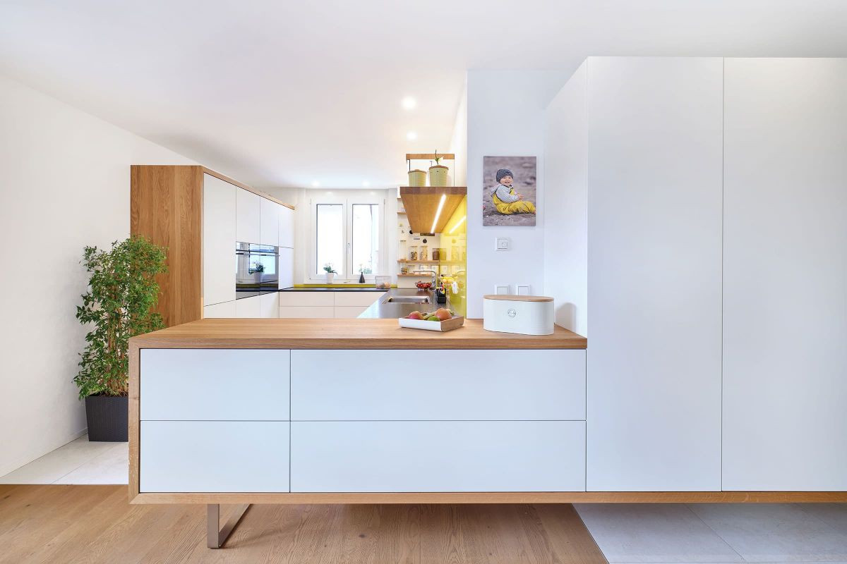 Moderne altersgerechte Küche mit raumhohem Schrank und Eiche-Passepartout als Raumteiler, grifflose Fronten und integrierte Geräte