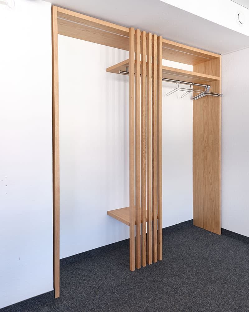 Eine maßgefertigten Garderobe mit Holzlamellen im Eingangsbereich, gefertigt von der Echaz Schreinerei