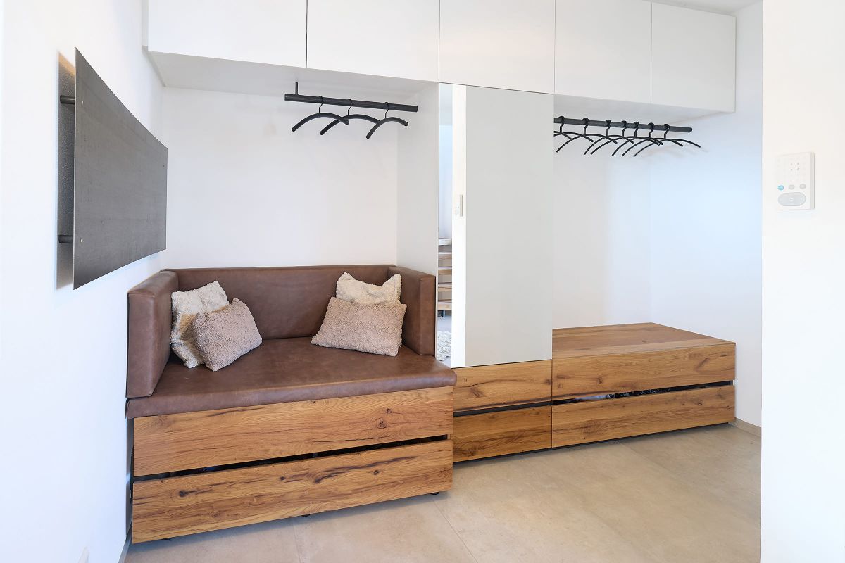 Moderner Eingangsbereich mit maßgefertigter Garderobe aus Holz, gepolsterter Sitzbank und großzügigem Spiegel.
