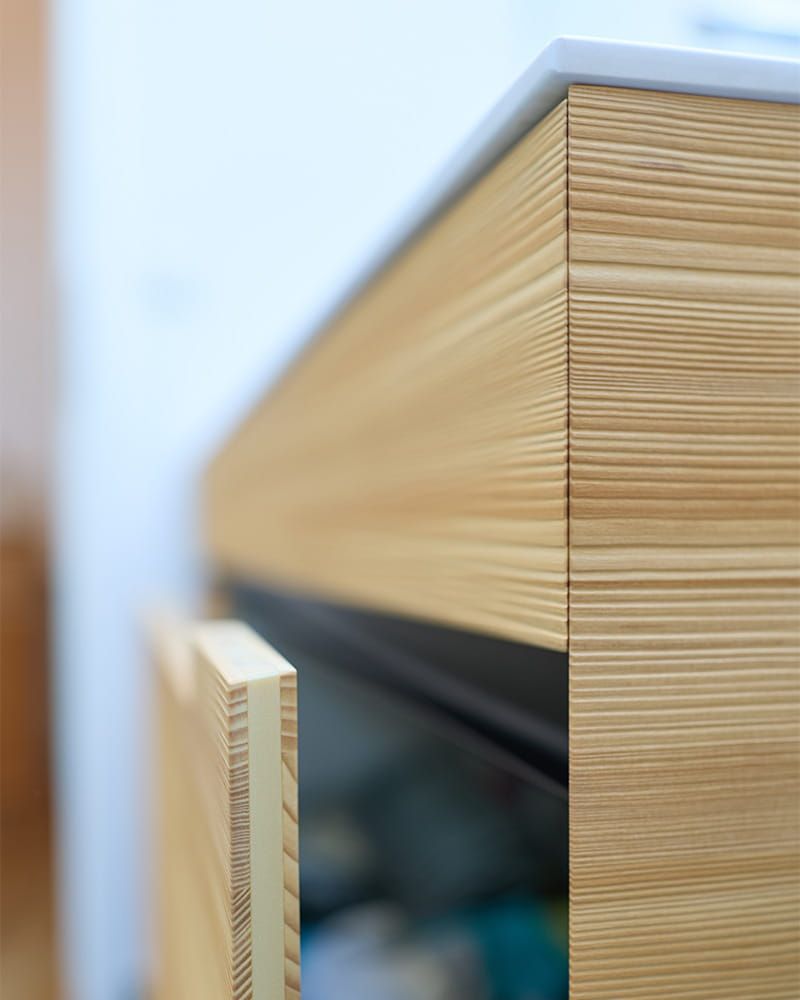 Nahaufnahme einer geöffneten Schublade aus hellem Holz mit filigraner Verarbeitung.