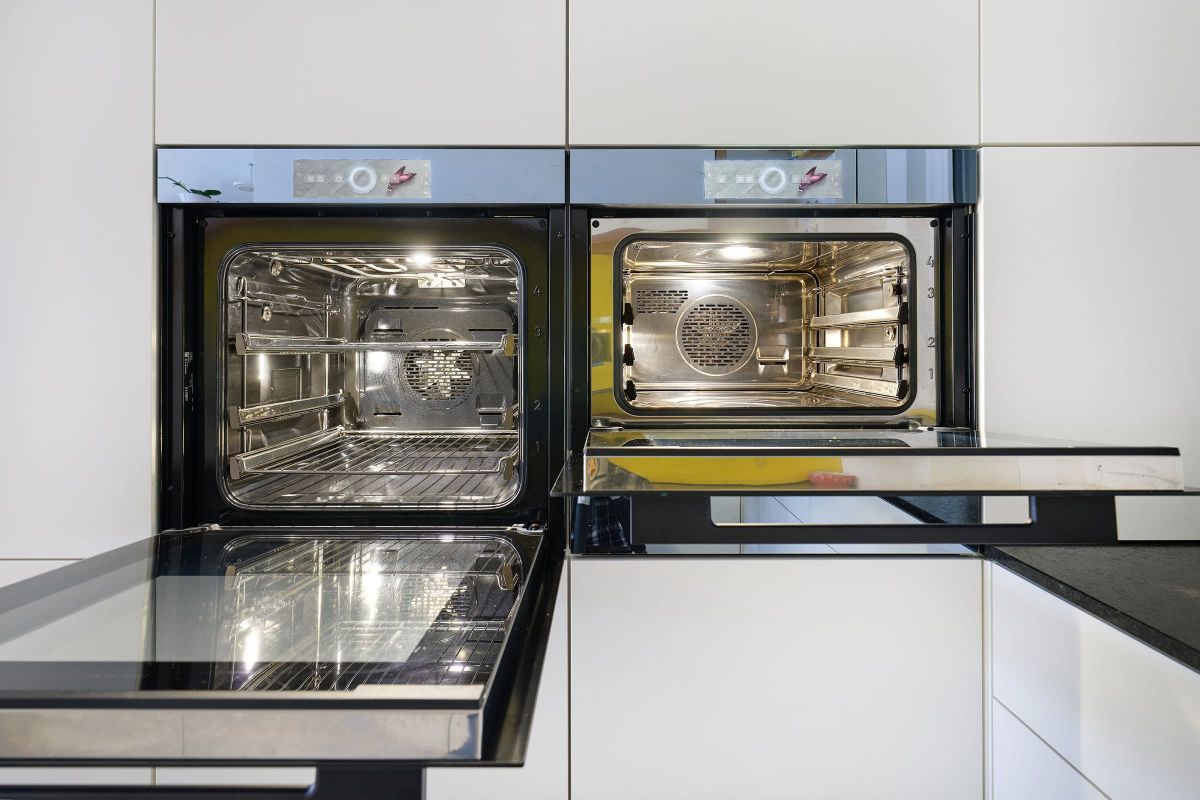 Moderne Küchengeräte integriert in einen maßgefertigten Hochschrank mit grifflosem Frontdesign