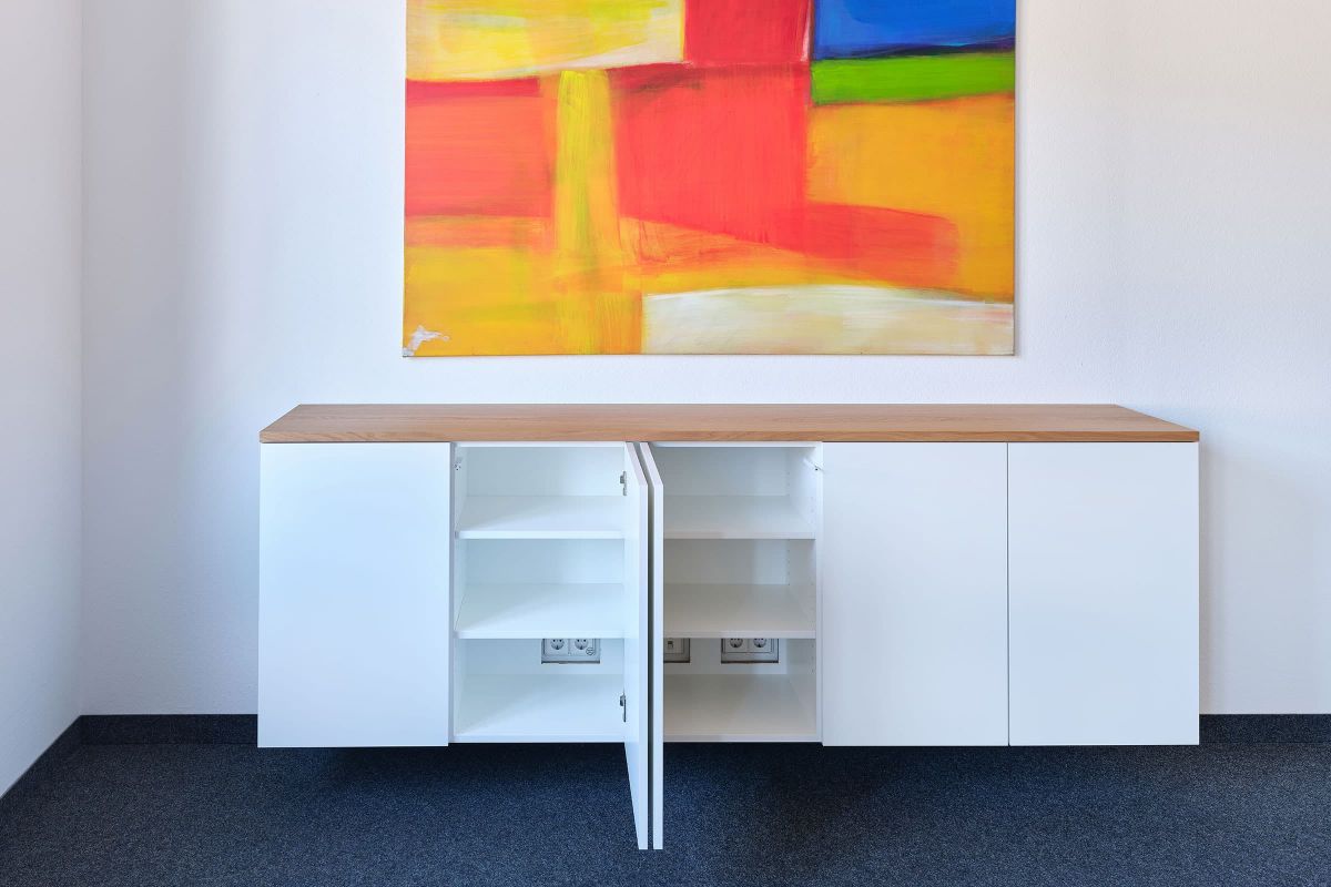Maßgefertigtes Sideboard mit weißen Fronten und Holzabdeckung im Büro, gefertigt von der Echaz Schreinerei