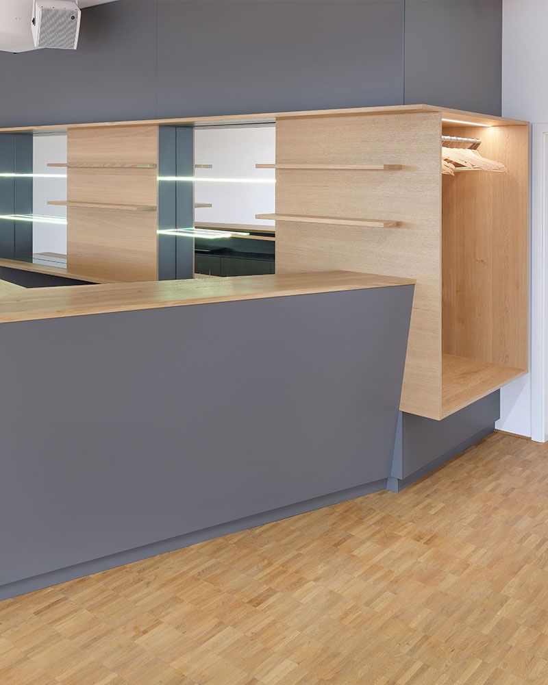Empfangsbereich mit maßgefertigtem Tresen und integrierter Garderobe aus der Echaz Schreinerei