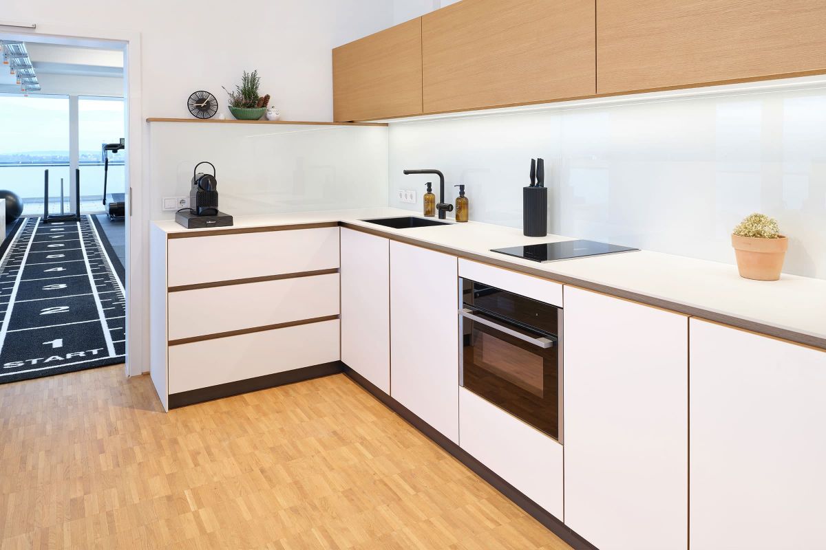 Hochwertige Praxisküche mit weißen Fronten und Holzdetails, individuell geplant und gefertigt von der Echaz Schreinerei