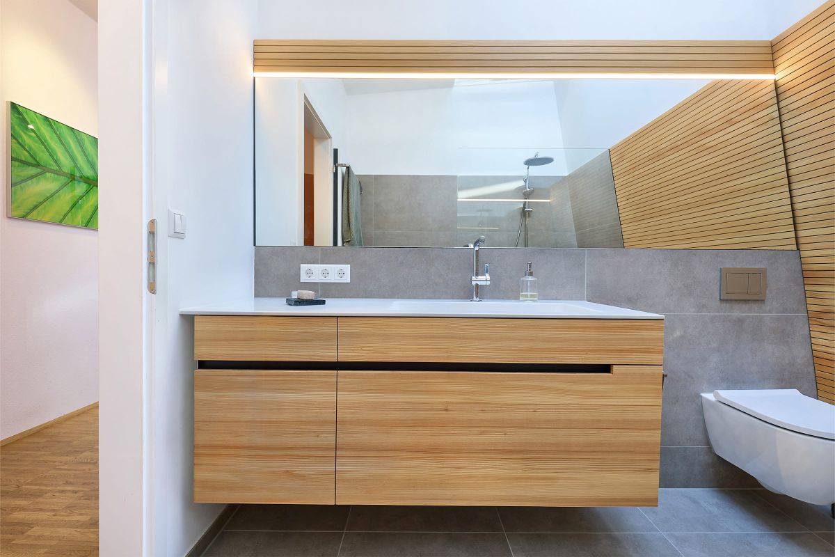 Modernes Badezimmer mit Holzwaschtisch, großem Spiegel und minimalistischen Details in hellen Naturtönen.