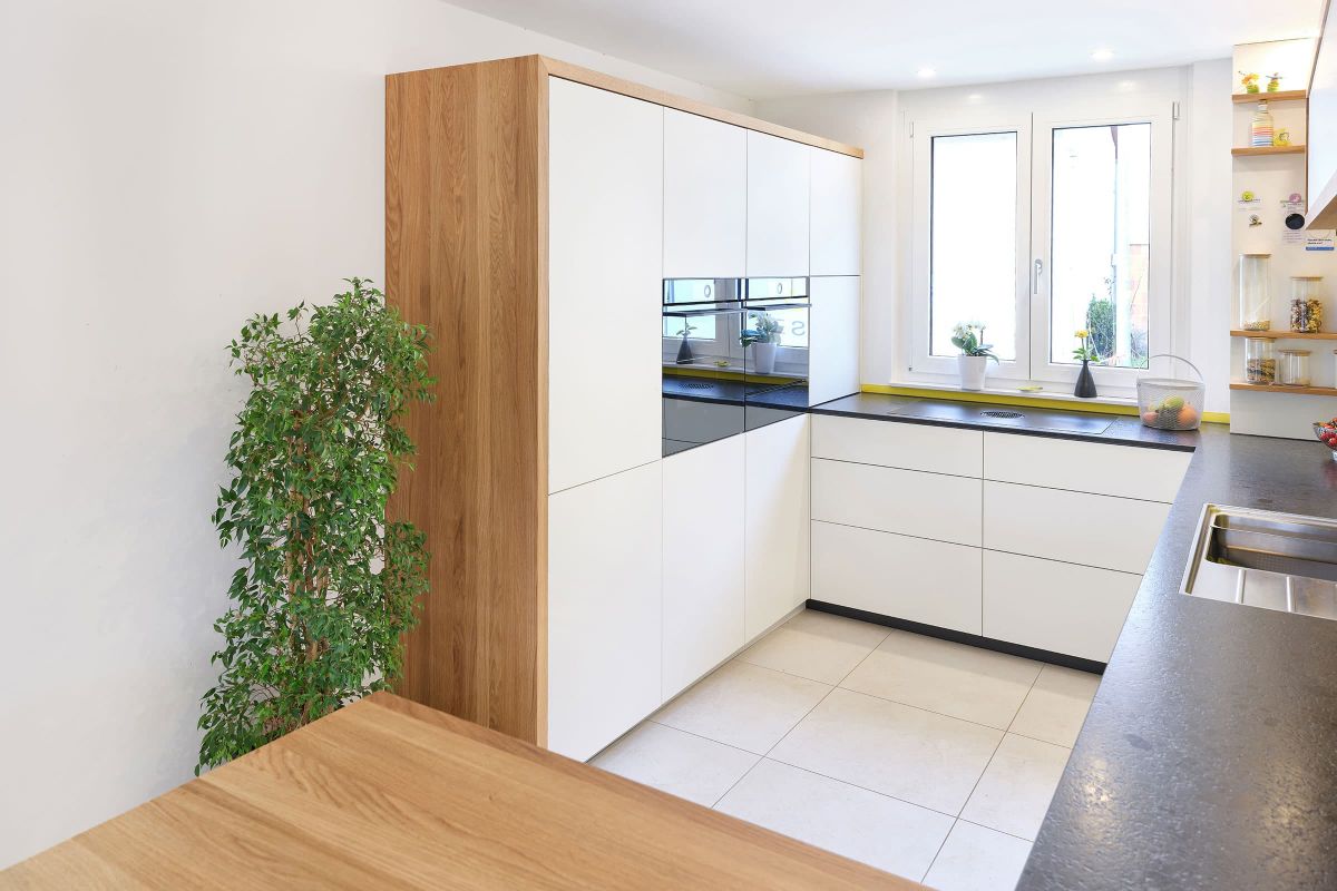 Moderne grifflose Schreinerküche mit Hochschrank, Eiche-Passepartout und dunkler Arbeitsplatte