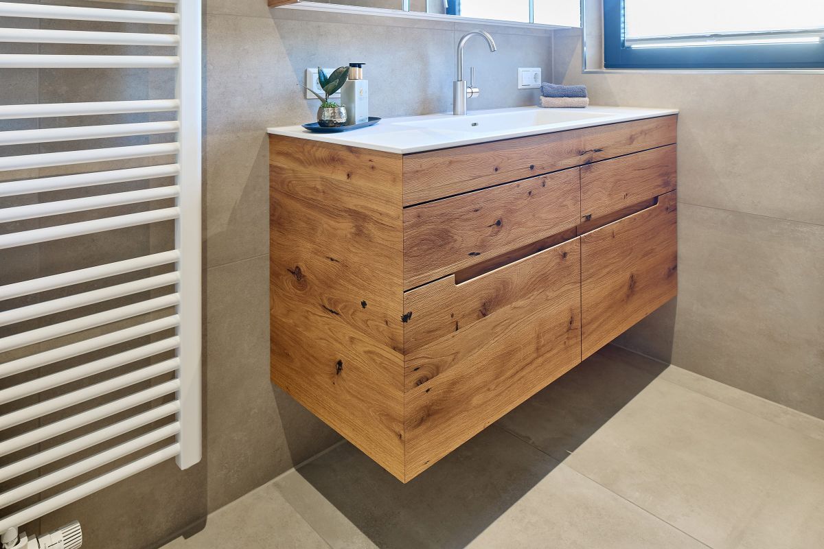 Moderner Waschtisch aus rustikalem Holz mit markanter Maserung, schwebend montiert in einem hellen Badezimmer.