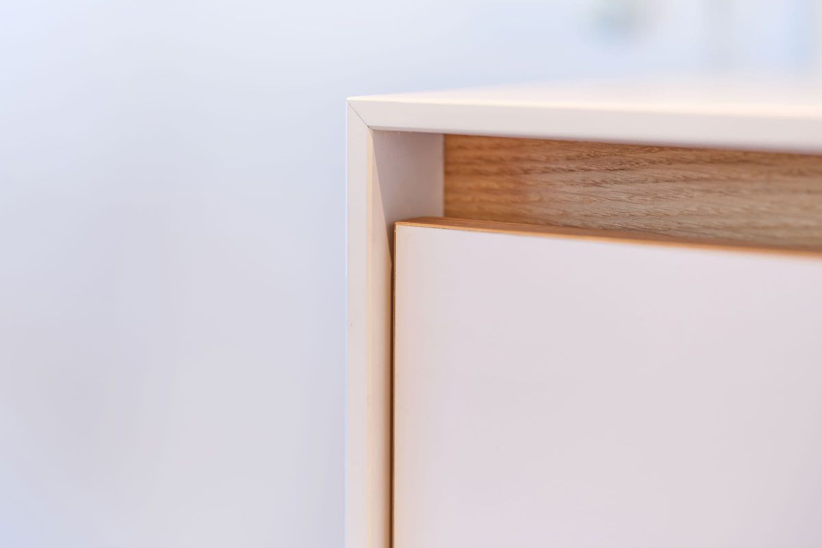 Detailansicht eines maßgefertigten Praxismöbels mit weißer Front und sichtbarer Holzkante aus der Echaz Schreinerei