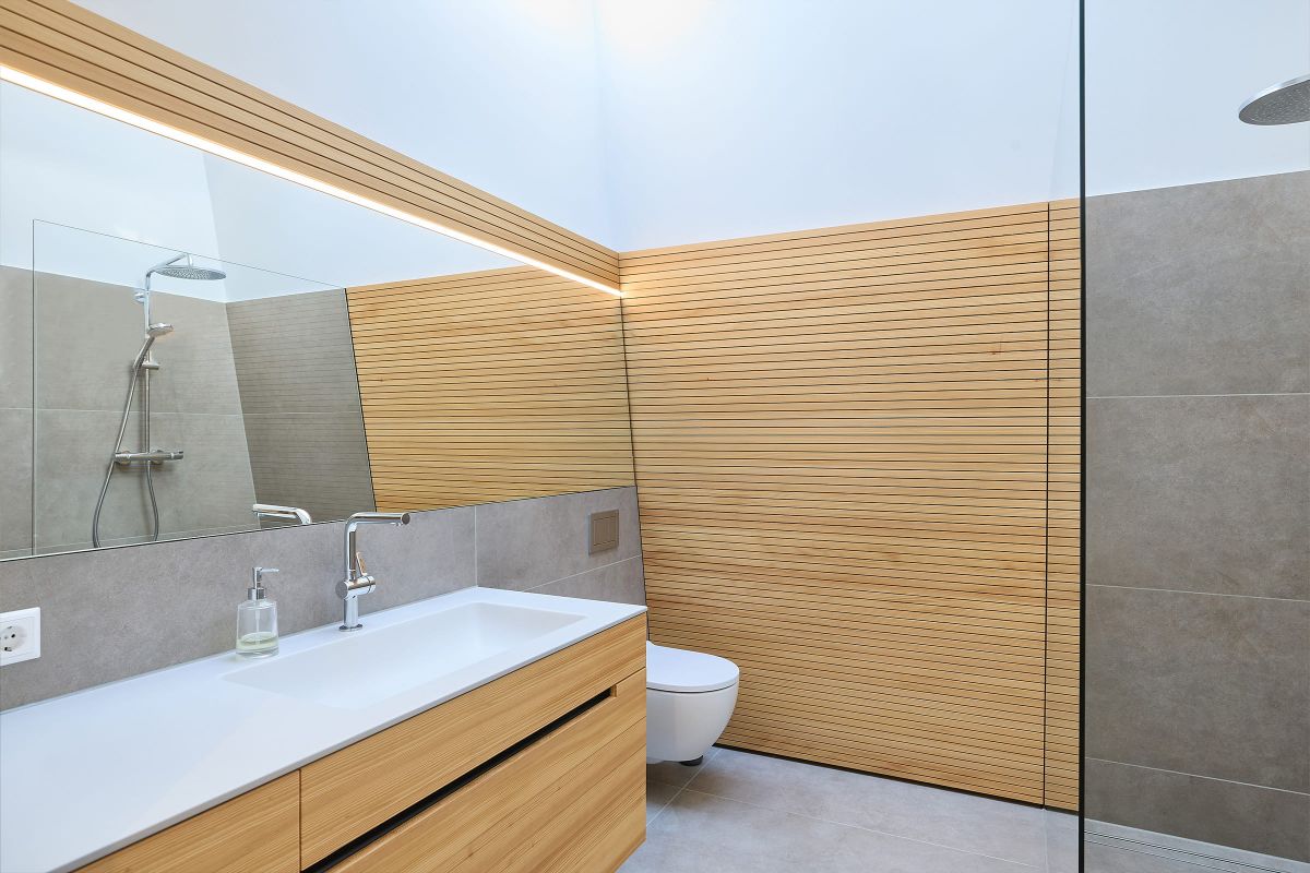 Helles Bad mit Holzpaneelen, großem Spiegel und minimalistischer Ausstattung.