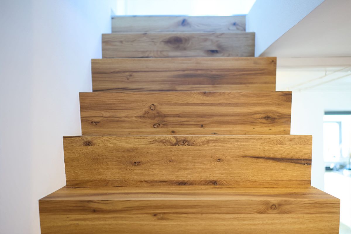 Detailaufnahme einer massiven Holztreppe mit lebendiger Maserung in einem modernen Wohnraum.